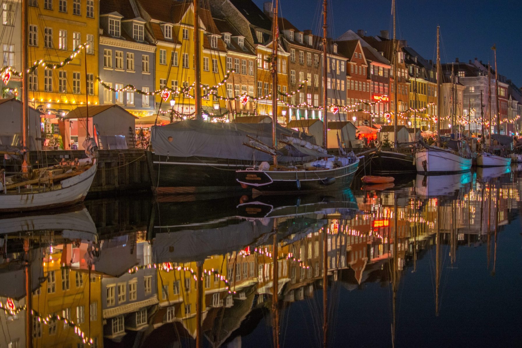 Colourful Copenhagen buildings and boats reflected in the water at night, showcasing the vibrant cityscape supported by NORDUnet and Denmark's NREN DeiC.