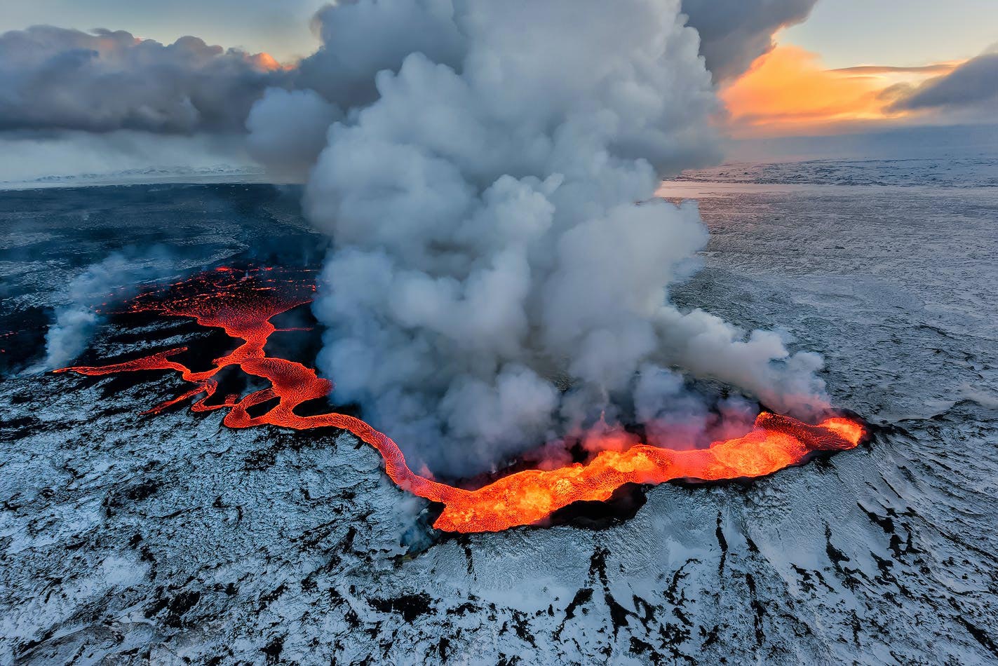Aerial view of an erupting volcano in Iceland with flowing lava and billowing smoke, illustrating the natural power and connectivity challenges addressed by NORDUnet and Iceland's NREN RHnet.