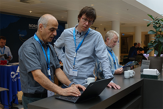 Two men at a NORDUnet conference, one typing on a laptop while the other observes